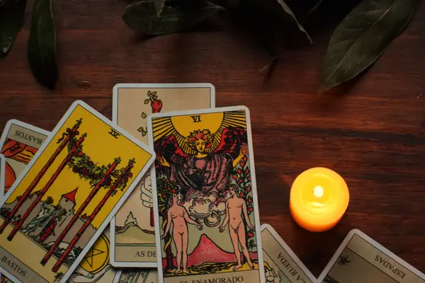 Cartes de tarot étalées sur une table en bois, à la lueur d'une bougie