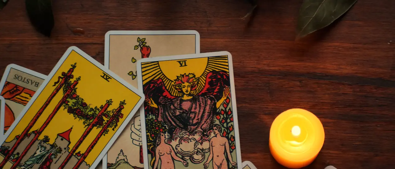 Cartes de tarot étalées sur une table en bois, à la lueur d'une bougie