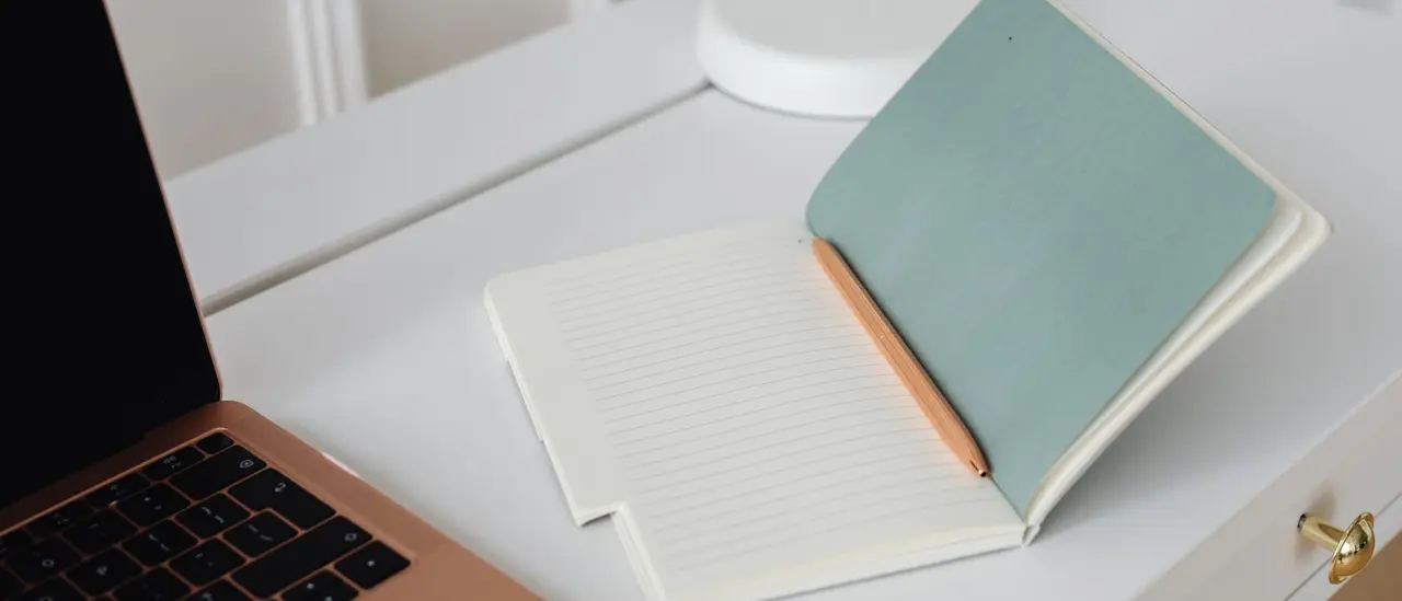 Carnet ouvert et stylo posés sur un bureau clair, pour formuler sa question