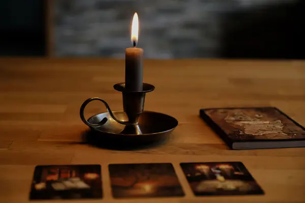 Bougie et cartes posées sur une table sombre, ambiance de tirage