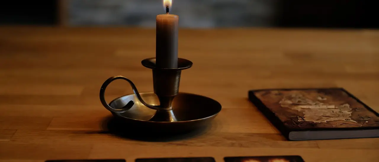 Bougie et cartes posées sur une table sombre, ambiance de tirage