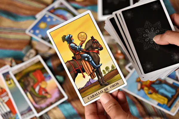 Cartes de tarot et pièces disposées sur un bureau, lumière chaude