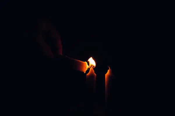 Mains éclairées par la flamme douce de bougies dans la pénombre