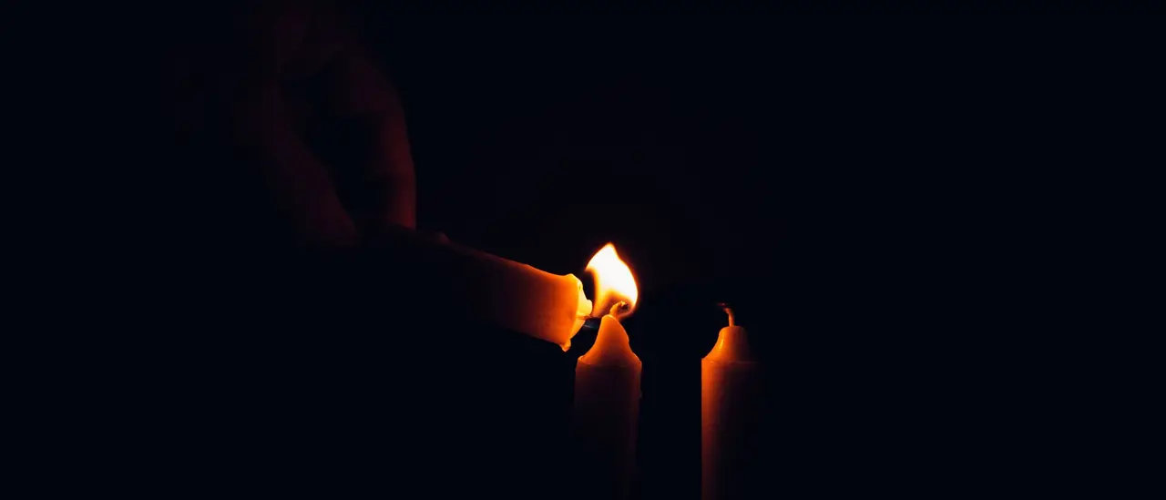 Mains éclairées par la flamme douce de bougies dans la pénombre