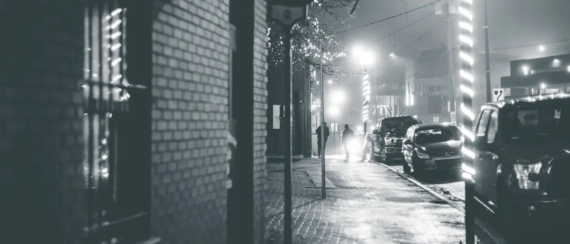 Rue urbaine déserte la nuit sous un éclairage froid, décor typique des récits modernes