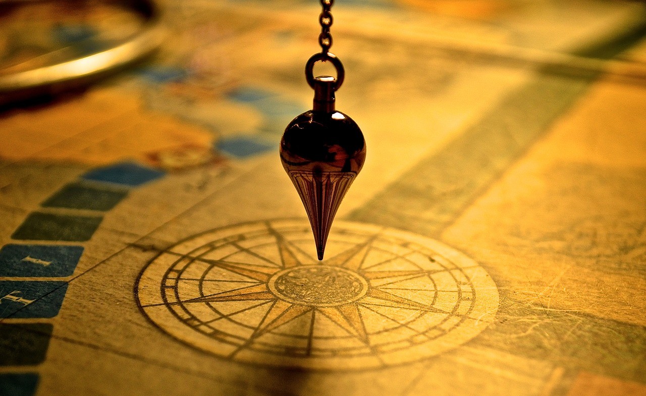 Pendule suspendu au-dessus d'une rose des vents gravée sur une vieille carte