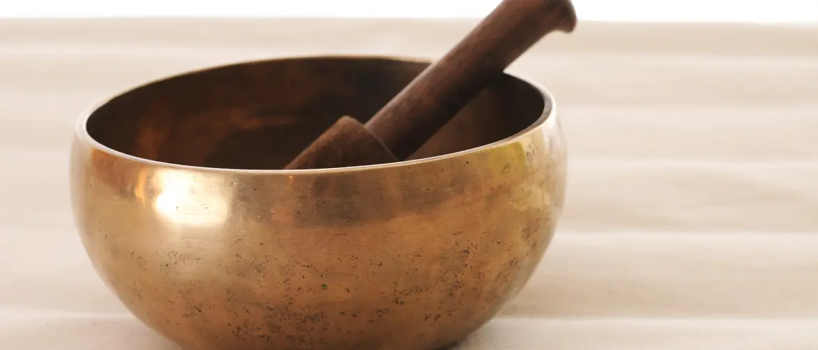 Bol tibétain en métal et son maillet de bois posés sur un tissu