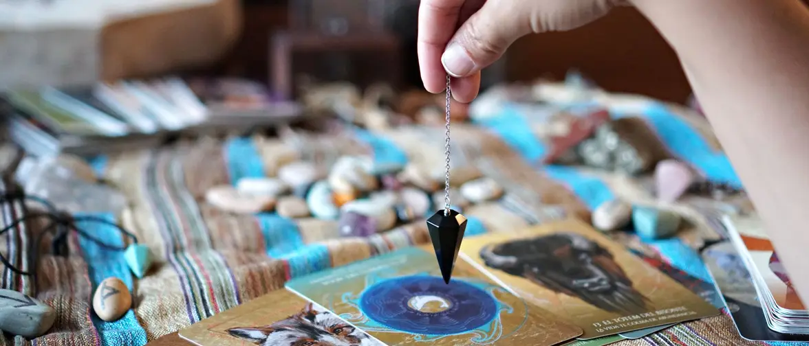 Pendule de radiesthésie tenu au dessus d'une surface claire